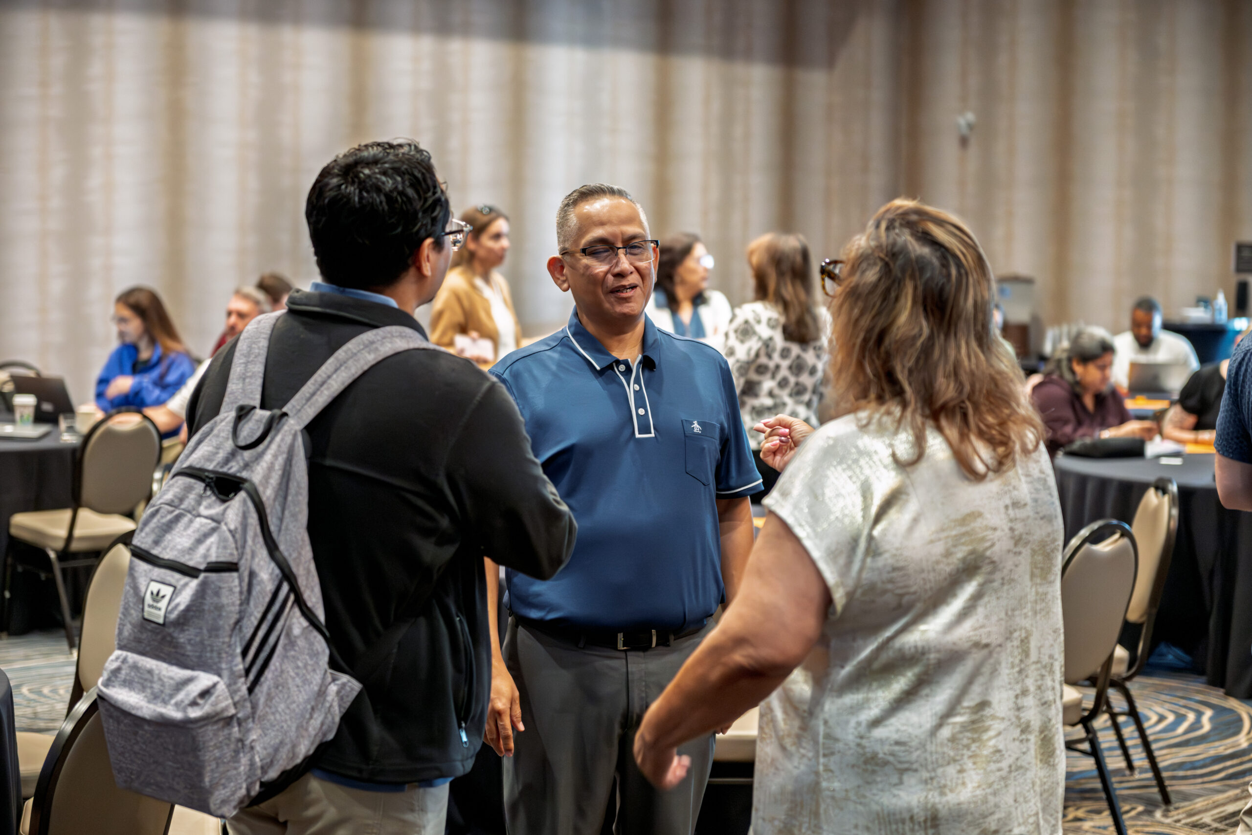 Aztec partner employer representatives engaging with an attendee at the Symposium vendor area