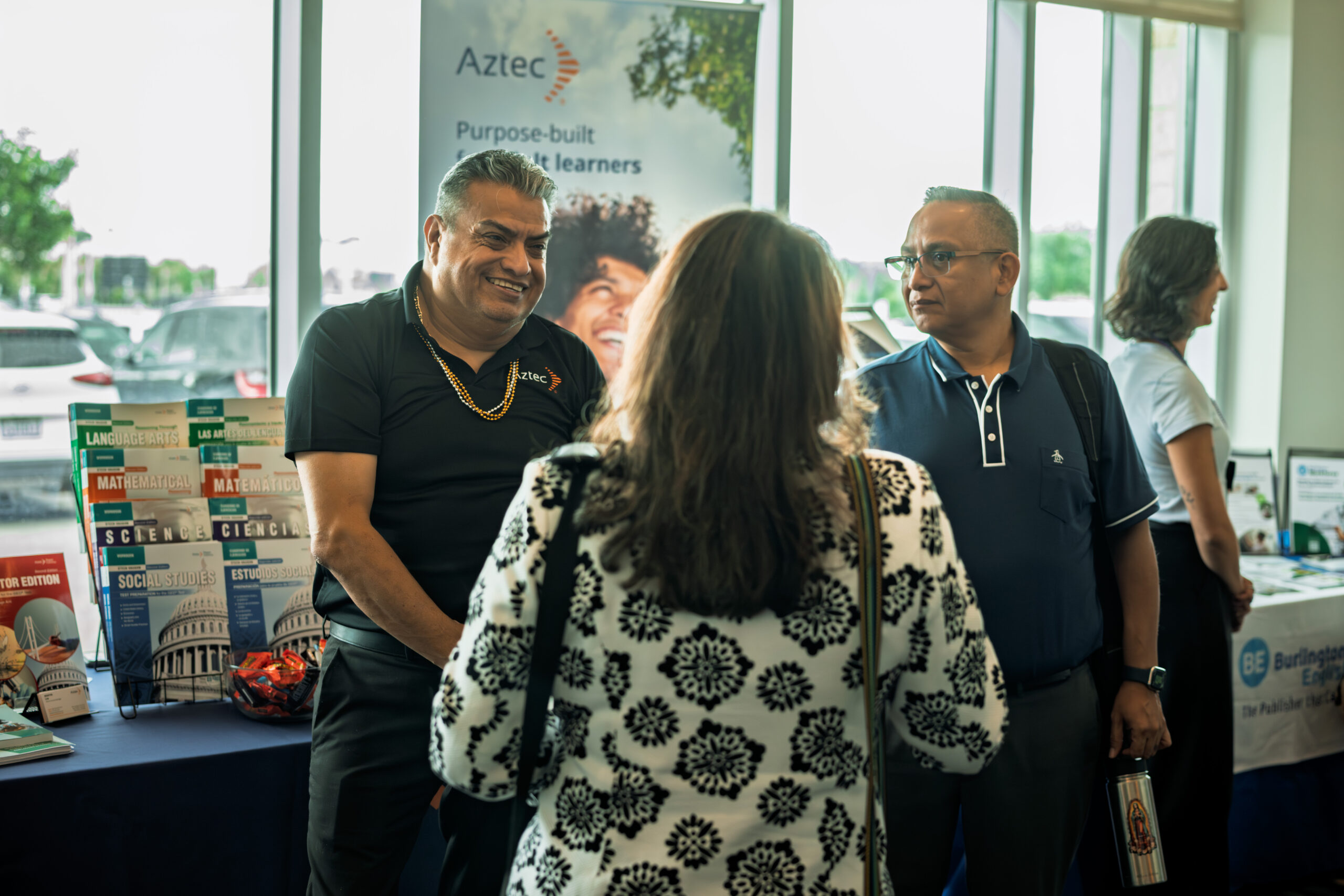Aztec partner employer representatives engaging with an attendee at the Symposium vendor area