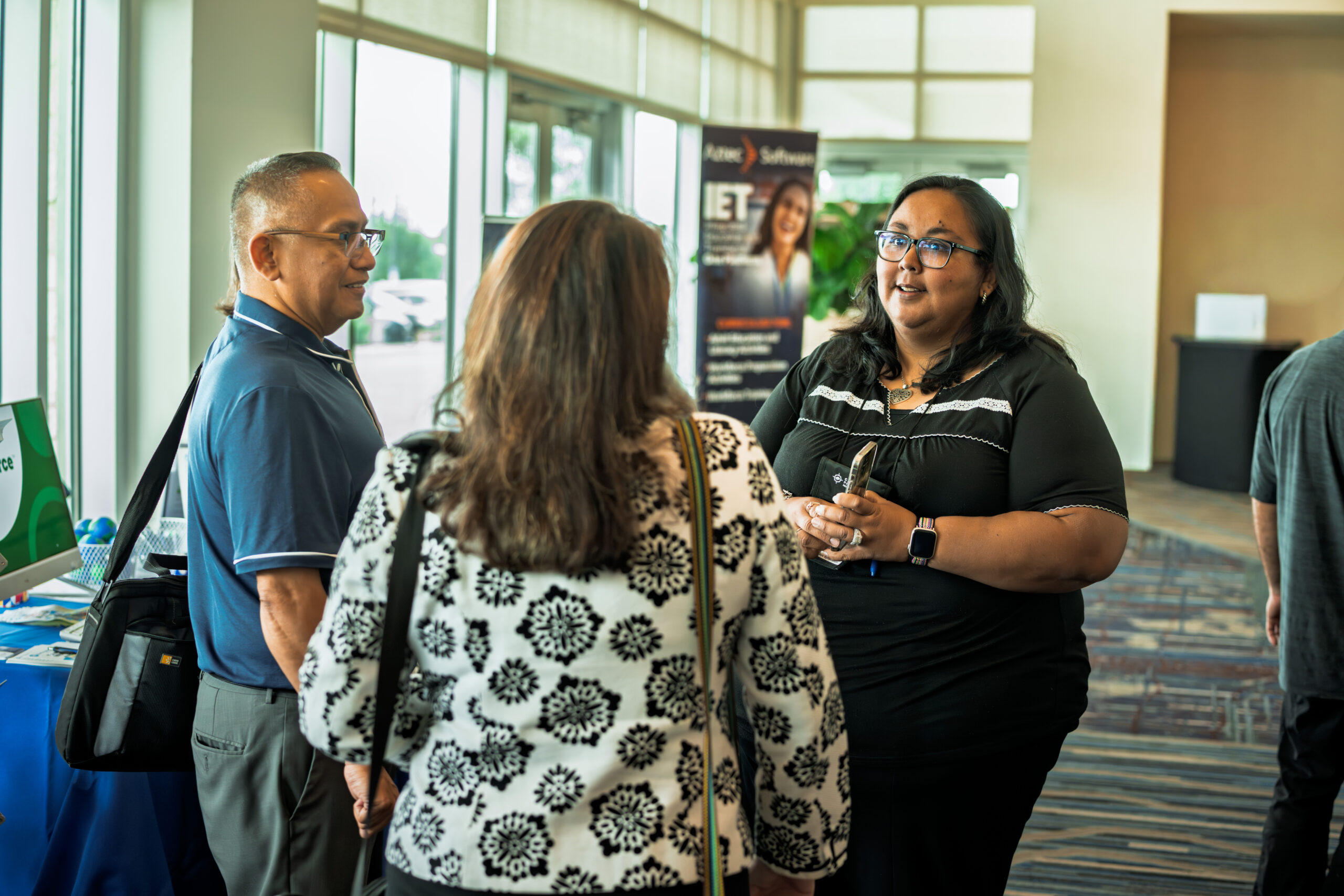 Aztec partner employer representatives engaging with an attendee at the Symposium vendor area
