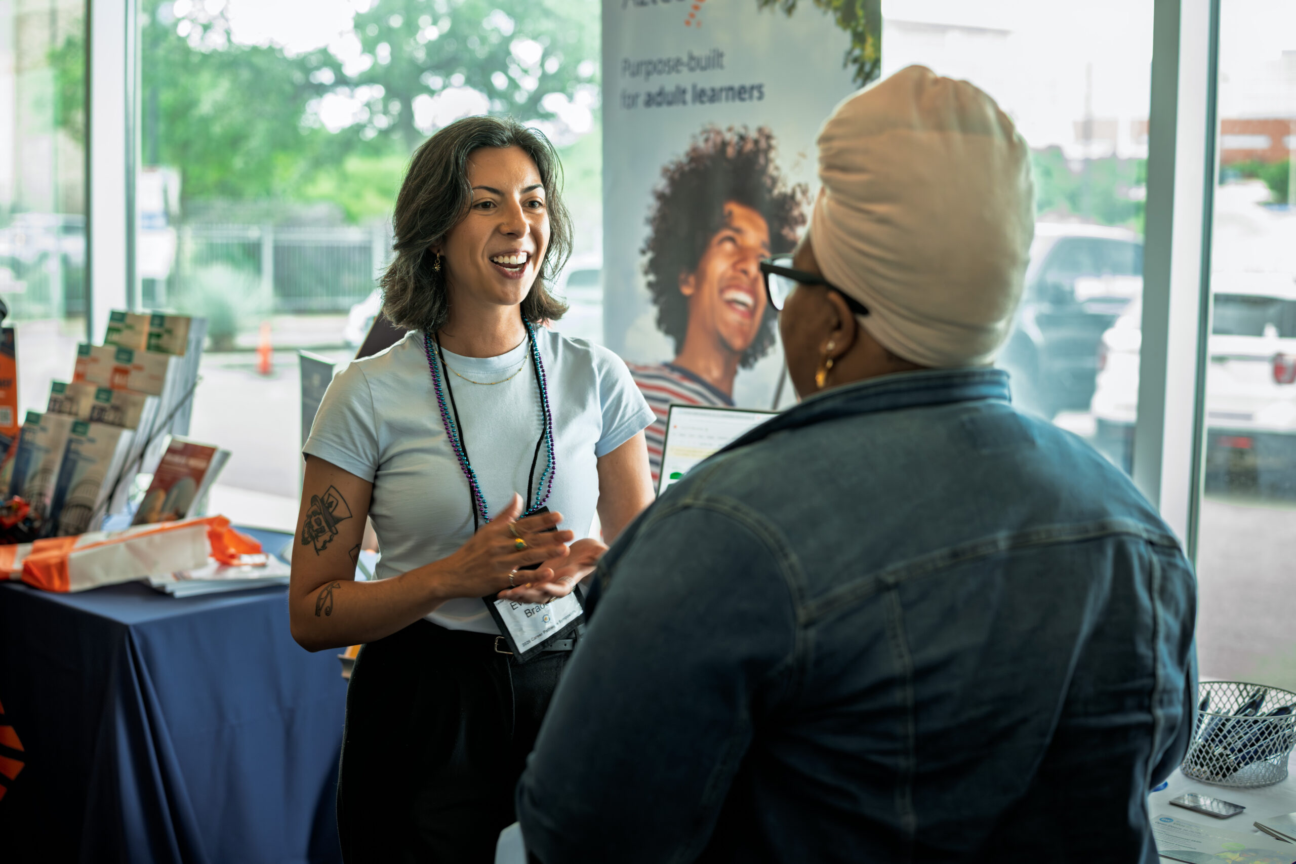 Symposium attendee smiling mid-conversation by a window during a networking moment